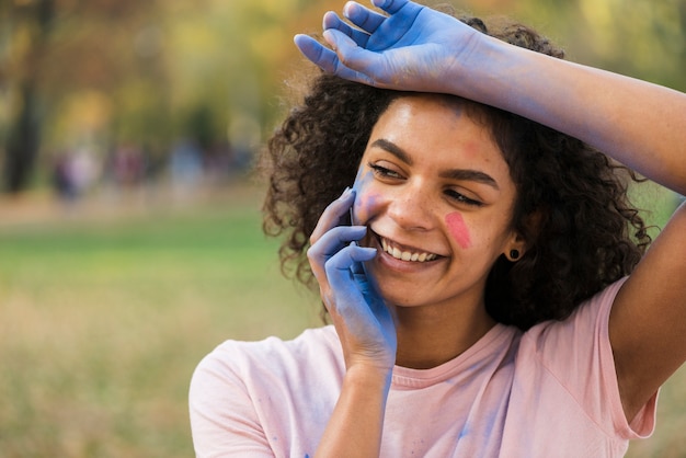 Frau, die mit den Händen bedeckt im blauen Pulver lächelt