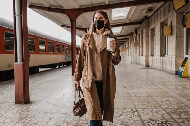 Frau, die mit einem Kaffee in einem Bahnhof geht