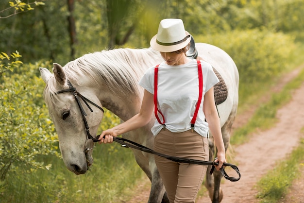 Kostenloses Foto frau, die mit einem pferd in der landschaft geht