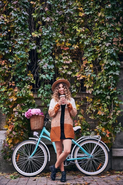 Frau, die mit Fahrrad nahe grüner Pflanzenwand aufwirft