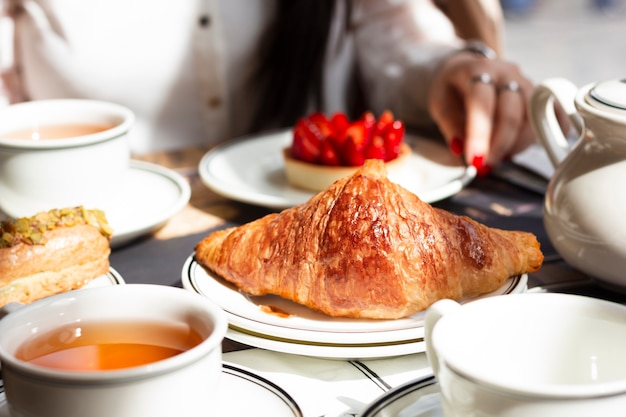 Frau, die mit Gebäckzusammenstellung frühstückt