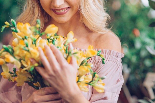 Frau, die mit gelbem Blumenblumenstrauß steht