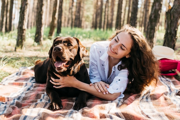 Frau, die mit ihrem Hund in der Natur sitzt