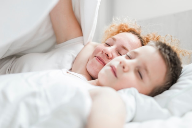 Frau, die mit ihrem Sohn auf Bett schläft