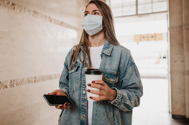 Kostenloses Foto frau, die mit kaffee und telefon in ihren händen geht