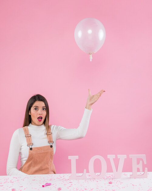 Frau, die mit Luftballon nahe Liebesaufschrift spielt