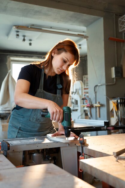 Frau, die mit mittlerem Schuss des Bohrers arbeitet