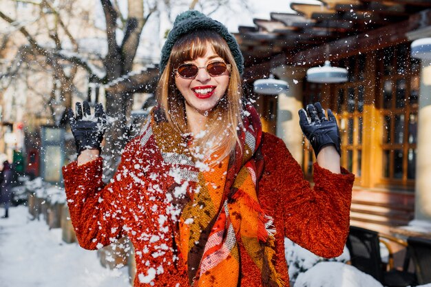 Frau, die mit Schnee spielt, Spaß hat und Feiertage genießt