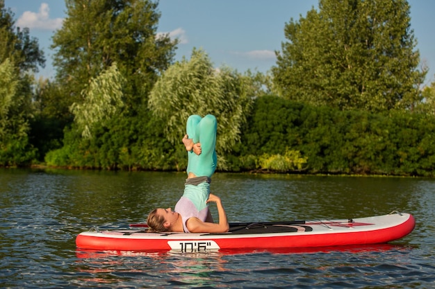 Frau, die morgens Yoga auf dem Paddelbrett praktiziert. Sport. Hobby. Yoga.