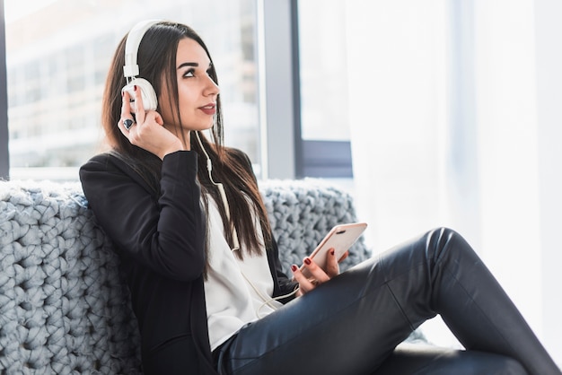 Kostenloses Foto frau, die musik auf sofa hört