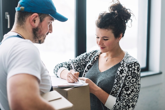 Frau, die nach dem Empfangen des Pakets mit Kurier unterzeichnet