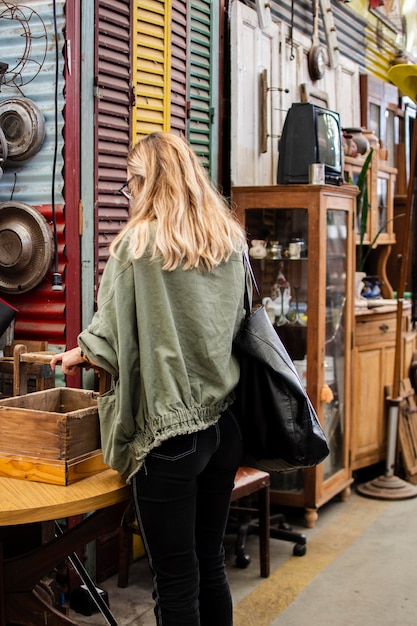 Kostenloses Foto frau, die nach etwas sucht, um in einem antiquitätenmarkt zu kaufen