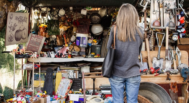 Frau, die nach etwas sucht, um in einem Antiquitätenmarkt zu kaufen