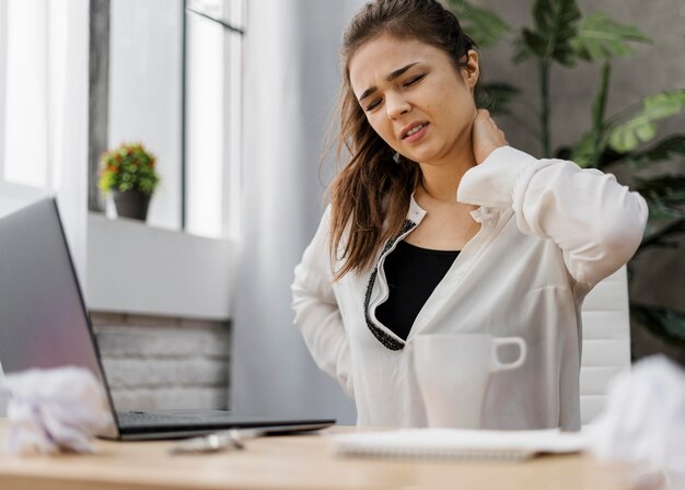 Frau, die Nackenschmerzen beim Arbeiten zu Hause hat