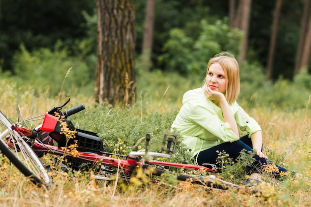 Frau, die nahe bei Fahrrad sitzt und weg schaut