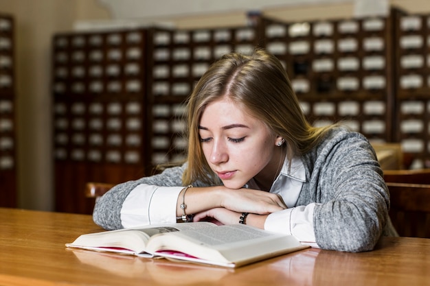 Kostenloses Foto frau, die nahe buch in der bibliothek schläft