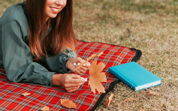 Frau, die neben einem Buch auf einer Picknickdecke bleibt