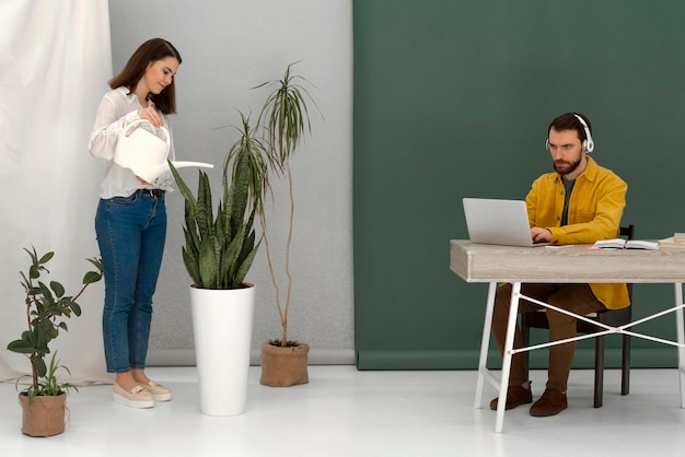 Frau, die Pflanze und Mann mit Laptop wässert