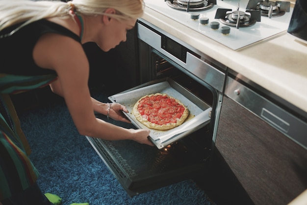 Frau, die Pizza an der Küche kocht