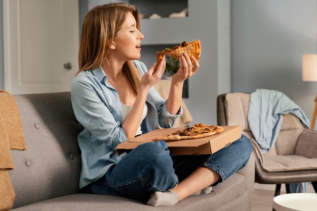 Frau, die Pizza beim Fernsehen isst