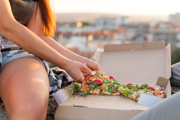 Frau, die Pizza draußen isst