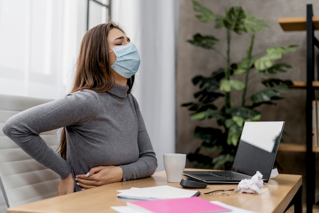 Frau, die Rückenschmerzen während der Arbeit zu Hause hat