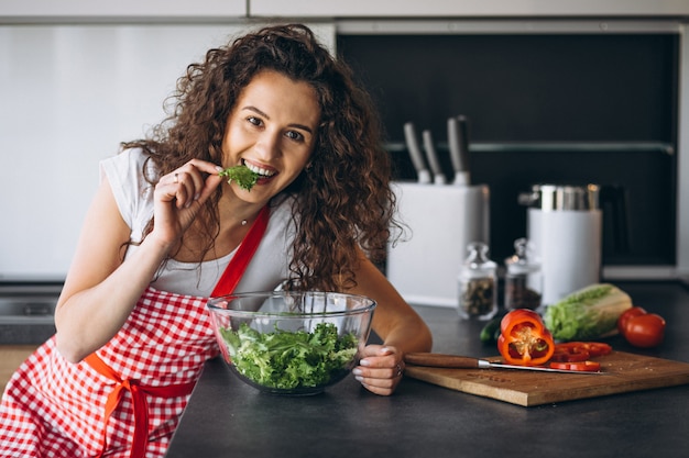 Frau, die salat an der küche macht