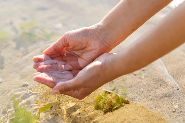 Frau, die sauberes Wasser in den Händen im Freien hält