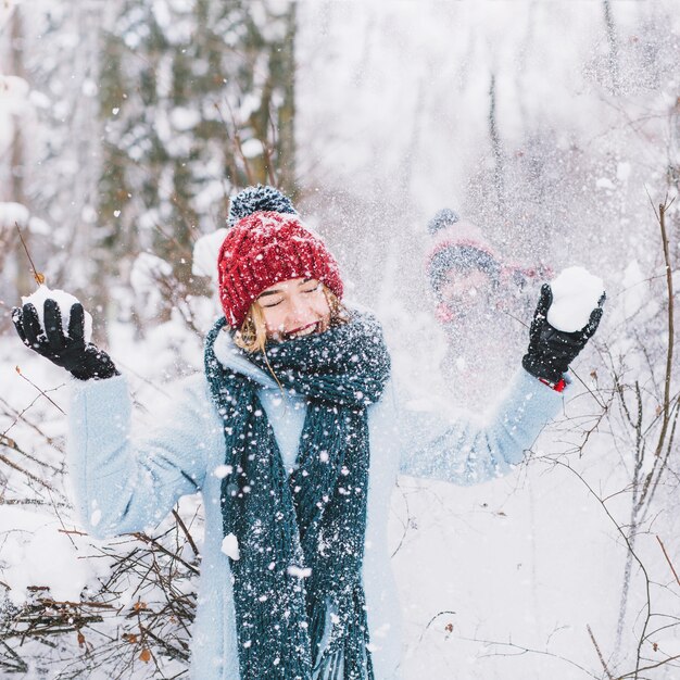 Frau, die Schneeballspiel im Wald verliert