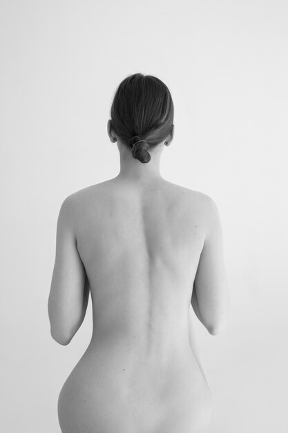 Frau, die Schwarzweiss-Nacktheitsrückansicht aufwirft