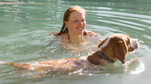 Frau, die schwimmt und mit Hund im Wasser spielt