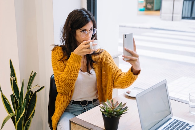 Frau, die selfie mit Cup in der Cafeteria erhält