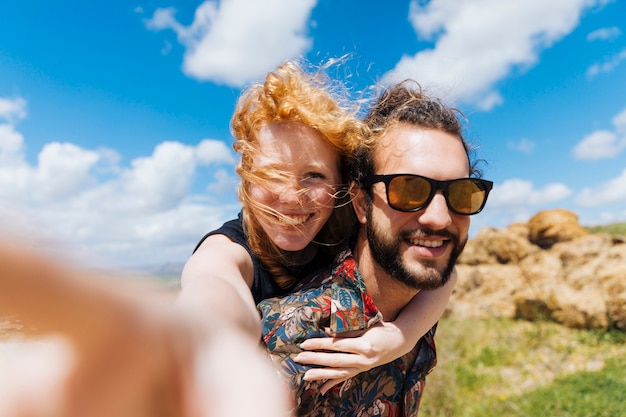 Kostenloses Foto frau, die selfie nimmt und ein vom mann zurück sitzt