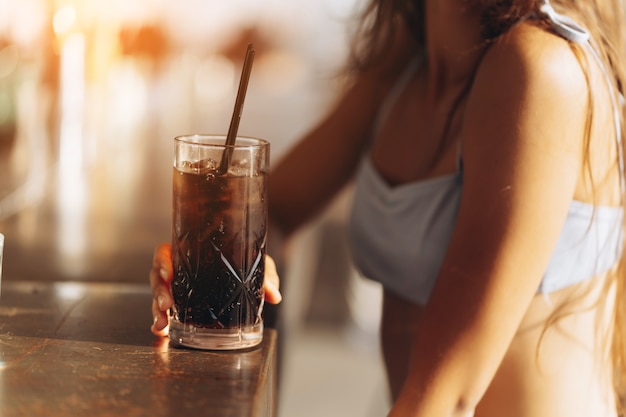 Frau, die sich auf der Strandbar ausruht, trinkt einen erfrischenden Cocktail