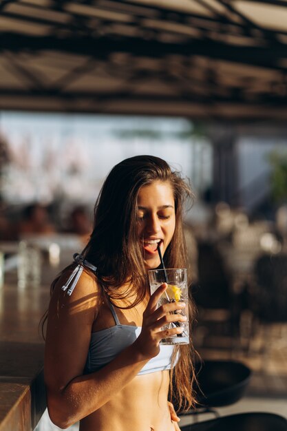 Frau, die sich auf der Strandbar ausruht, trinkt einen erfrischenden Cocktail