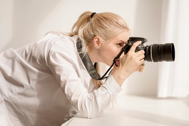 Frau, die sich auf Fensterbank stützt und ein Foto macht