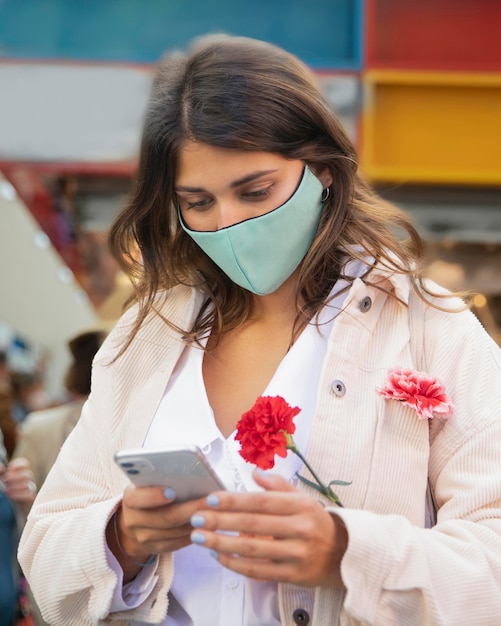 Kostenloses Foto frau, die smartphone beim halten von blumen verwendet