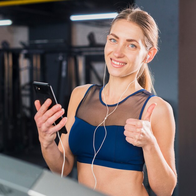 Frau, die Smartphone in der Turnhalle verwendet