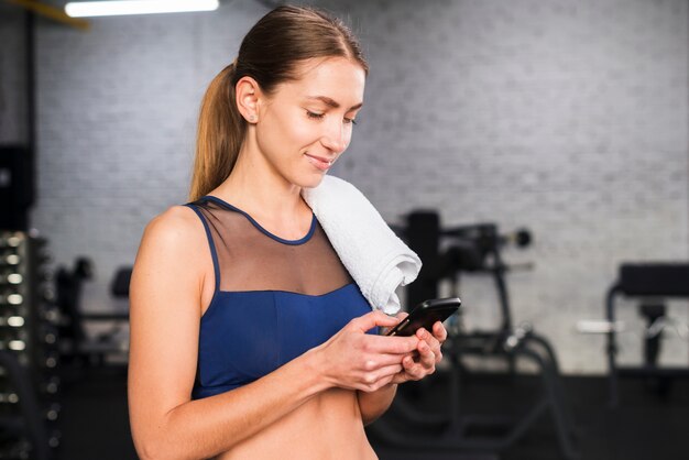 Frau, die Smartphone in der Turnhalle verwendet