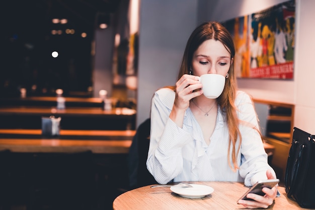 Kostenloses Foto frau, die smartphone trinkt und verwendet