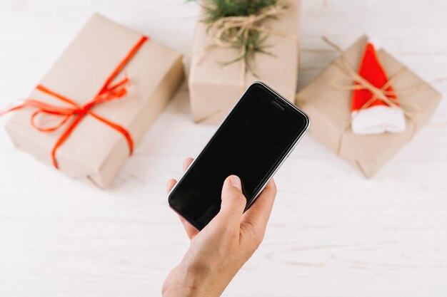 Kostenloses Foto frau, die smartphone über geschenkboxen hält