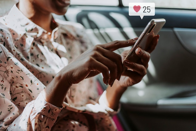 Frau, die soziale Medien auf ihrem Smartphone verwendet, während in einem Auto