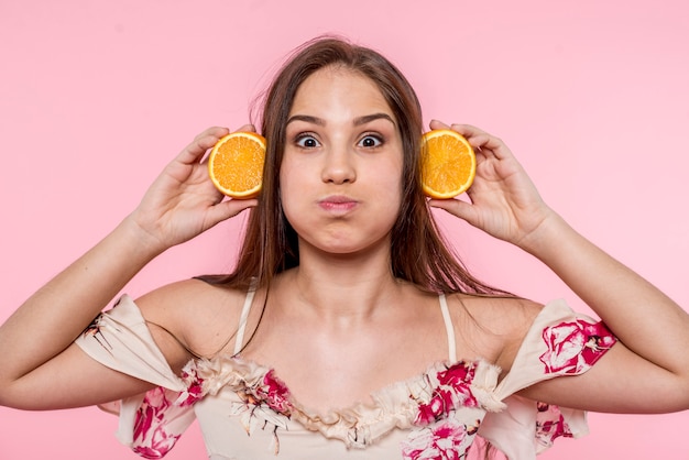 Kostenloses Foto frau, die spaß mit geschnittener orange gesicht verzieht und hat