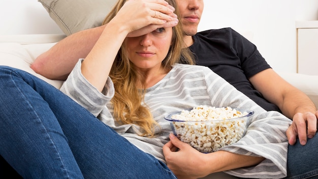 Frau, die speisendes Popcorn beim Fernsehen zu Hause halten hält