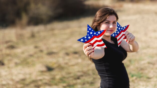 Frau, die Sterne der amerikanischen Flagge hält und Kamera betrachtet