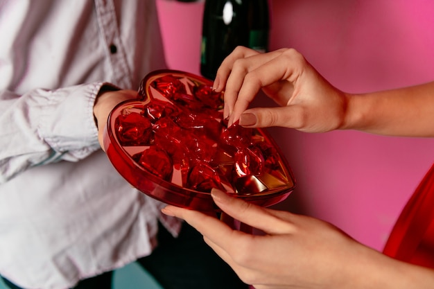 Frau, die Süßigkeiten in der Kastenform des Herzens von ihrem Freund am Valentinstag erhält.