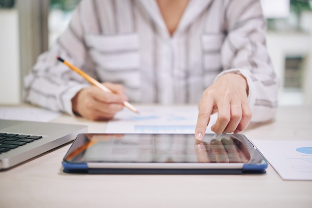 Frau, die Tablette beim Arbeiten verwendet