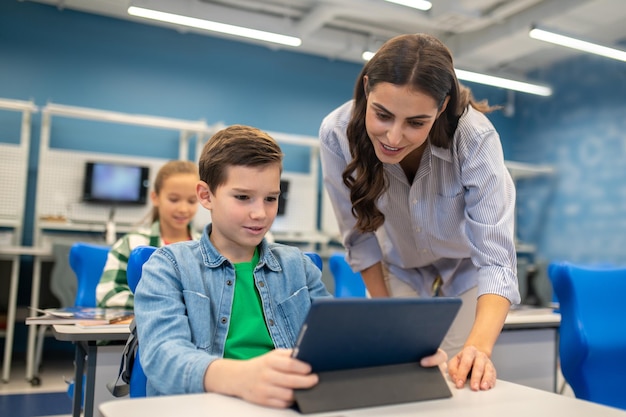 Kostenloses Foto frau, die tablette des studentenjungen untersucht