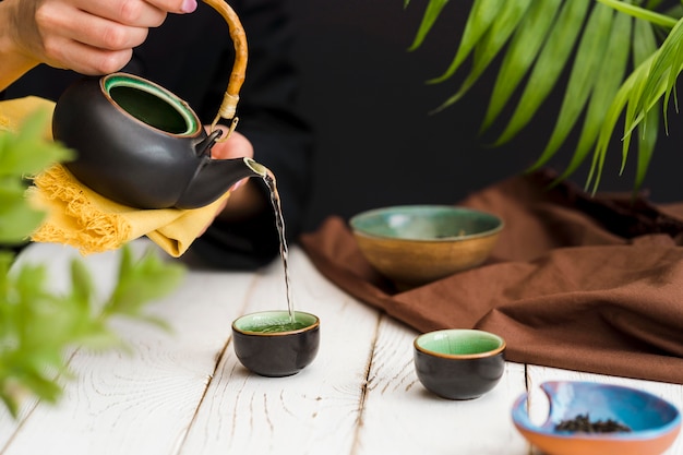 Frau, die Tee in kleine Tasse gießt