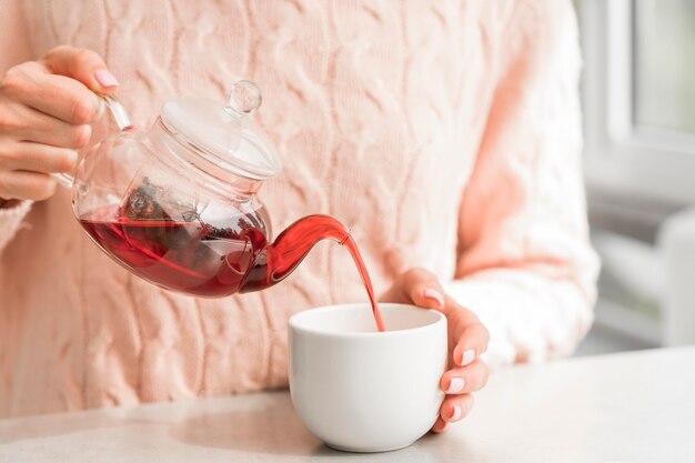 Frau, die Tee in Tasse gießt